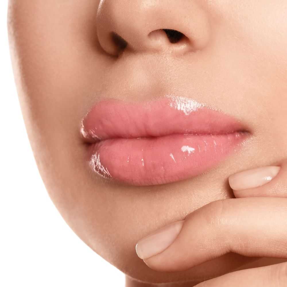 Close-up of a woman's pink glossy lips and chin.