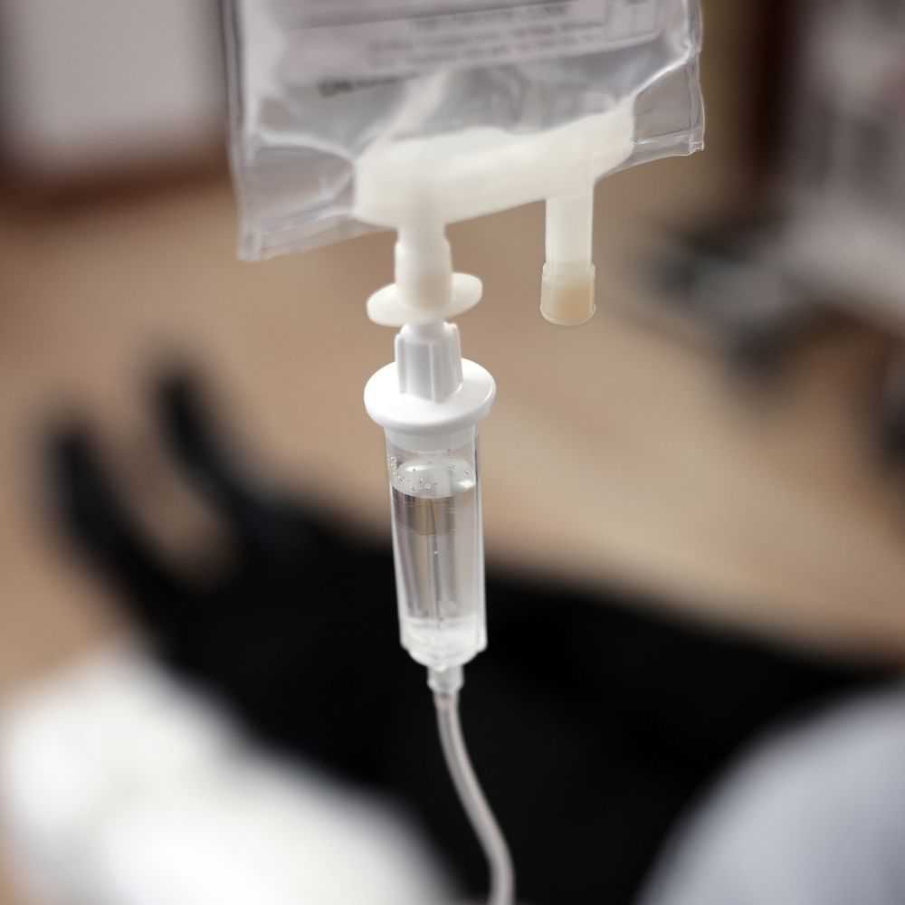 IV drip bag and tube administering medical fluid.