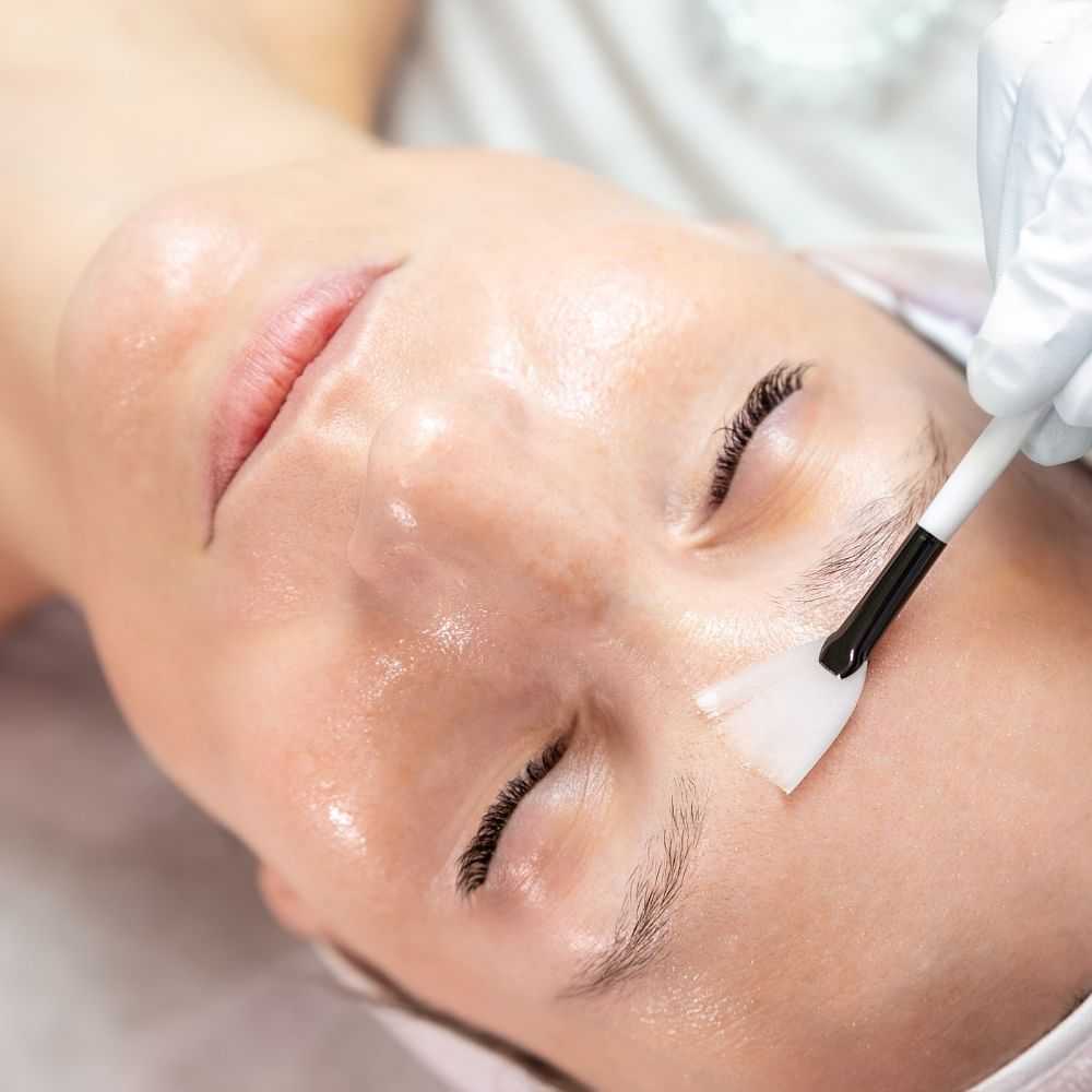 Close-up of a person receiving a facial treatment with a brush.