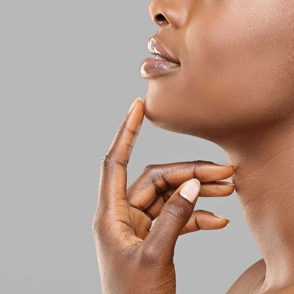 Profile of a woman with her finger on her chin, clear skin.