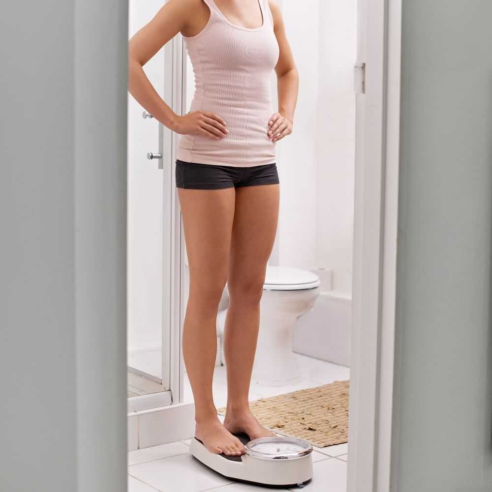 Woman weighing herself in the bathroom.