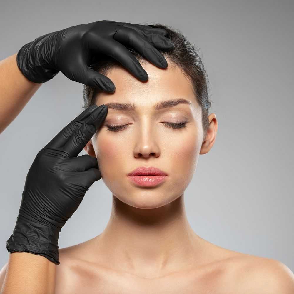 Aesthetician evaluating a woman's face before a procedure.